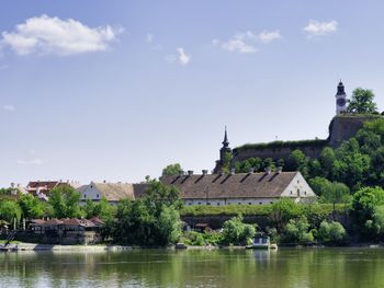Buildings by lake against sky