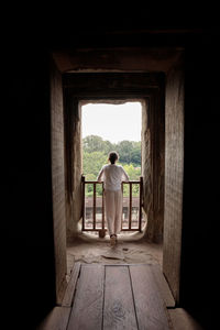 Rear view of woman standing at window in old ruins