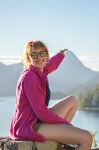 Portrait of woman sitting on mountain against sky