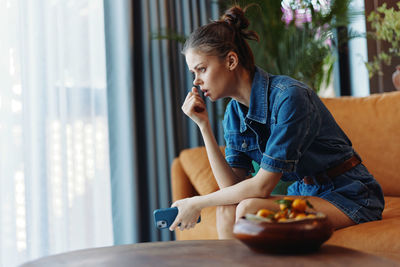 Young woman looking away while sitting on table