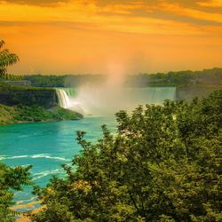 Scenic view of waterfall against sky during sunset