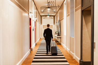 Rear view of man walking in corridor of building