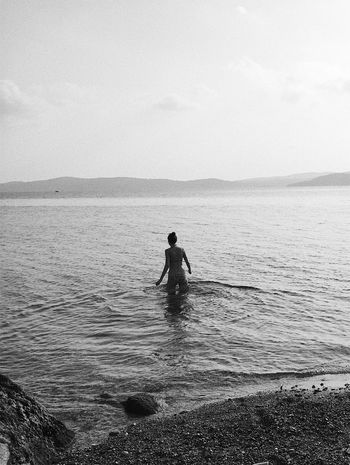Rear view of woman in sea against sky