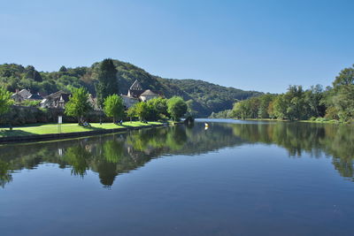 Scenic view of lake by trees against clear blue sky