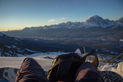 Low section of man sitting on mountain against sea