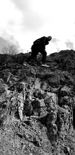 Low angle view of dog on rock against sky