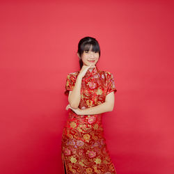 Portrait of a smiling young woman against red background