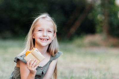 Portrait of smiling girl eating food at park