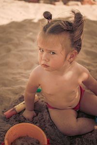 Portrait f girl sitting on sand at beach