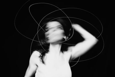 Blurred motion of woman with light painting against black background