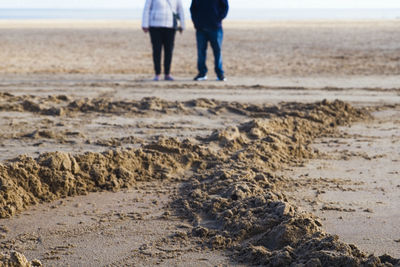 Out of focus couple standing on a beach showing just the lower half of them