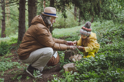 Grandfather showing mushroom to granddaughter in forest
