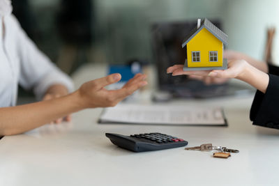 Midsection of woman receiving model house from agent