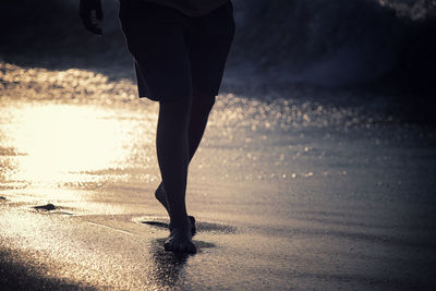Low section of silhouette man standing on beach