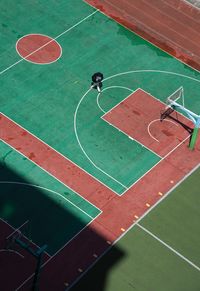 High angle view of person holding umbrella walking on basketball court