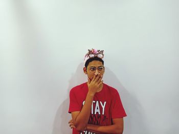 Teenage boy wearing headwear standing against white wall