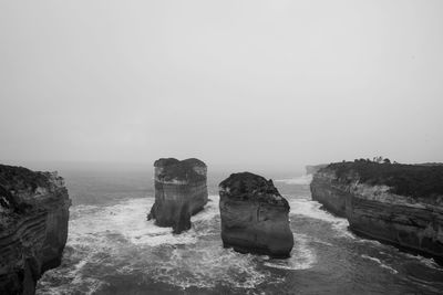 Aerial view of rock formations in sea against clear sky