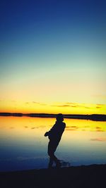 Silhouette man on beach against sky during sunset