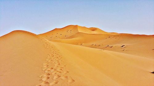 Sand dunes in desert against clear sky