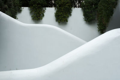 White fence made of successive staircases and plants hanging over it.