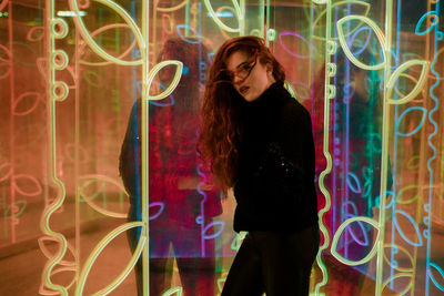 Young woman standing against illuminated lights at night