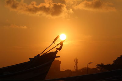 Silhouette boat moored in sea against orange sky. sunset between the boat captured on perfect timing