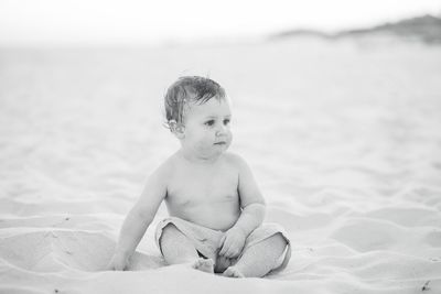 Boy sitting on sand at beach