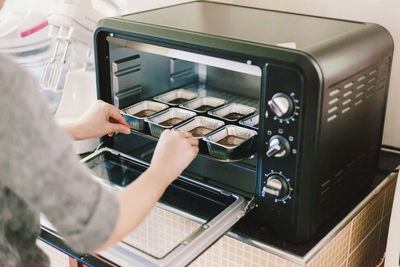 Cropped image of woman cooking food in oven