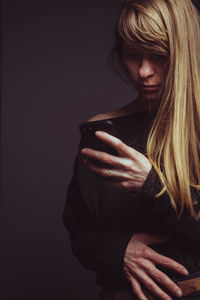 Midsection of woman holding hands against black background