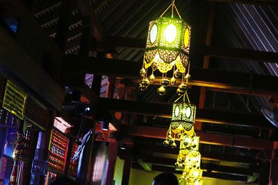 Low angle view of illuminated lights hanging from ceiling of building