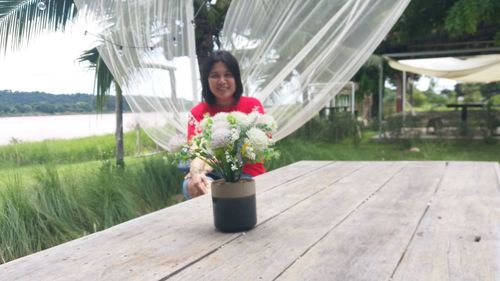 Portrait of woman standing by potted plant