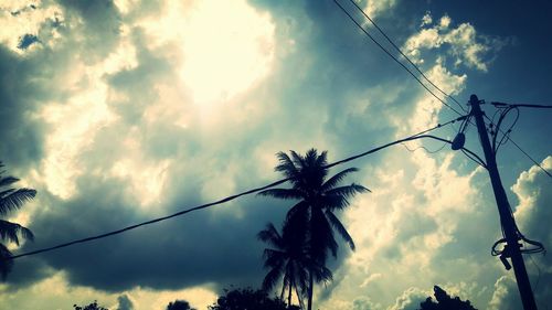 Low angle view of electricity pylon against cloudy sky