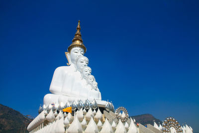 Low angle view of sculpture against building against clear blue sky