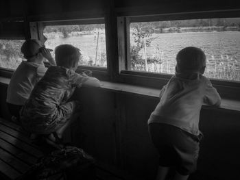 Rear view of brothers looking through window