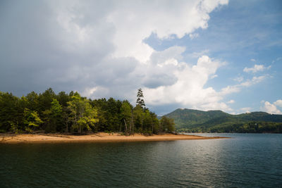 Scenic view of lake by trees against sky