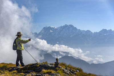 Rear view of man standing on mountain against sky