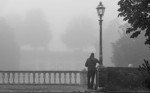 Man standing on bridge in fog