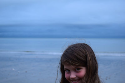 Portrait of girl at beach against sky