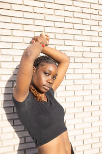 Young woman standing against brick wall