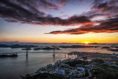 High angle view of sea and buildings against sky during sunset