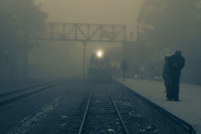 Man standing on railroad tracks against sky at night