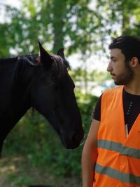 Man wearing reflective clothing standing by horse at farm