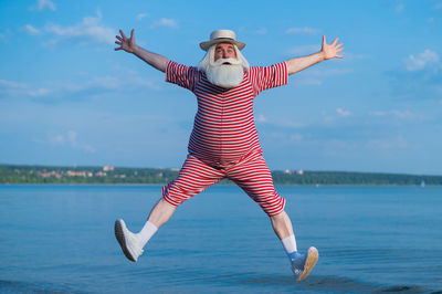 Woman in mid-air by sea against sky