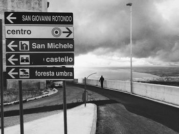 Road sign against cloudy sky