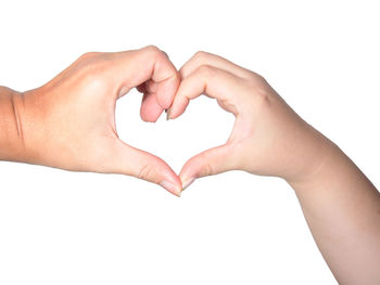 Close-up of hands making heart shape against white background