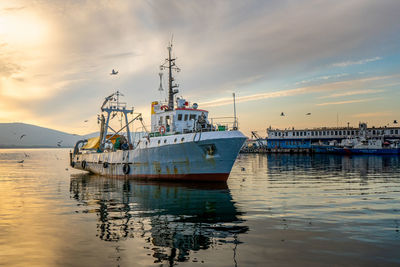 Fishing boats in sea against cloudy sky