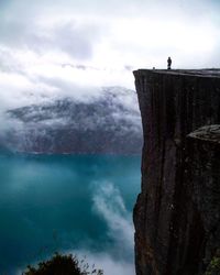 Distant view of man standing on huge cliff overlooking river
