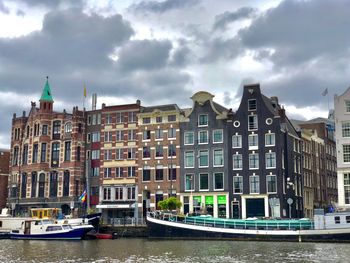 Buildings by canal against sky in city