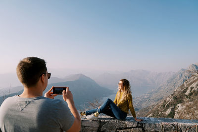 Side view of woman looking at mountains against clear sky