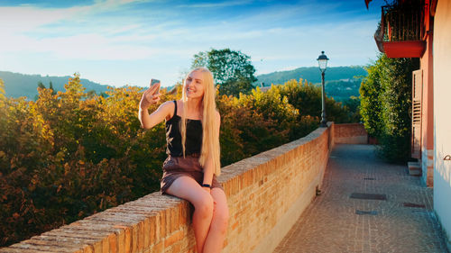 Low section of woman with arms raised against sky